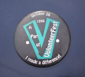 A pin from 1996 VolunteerFest- black background with a teal "V" and "I made a difference"